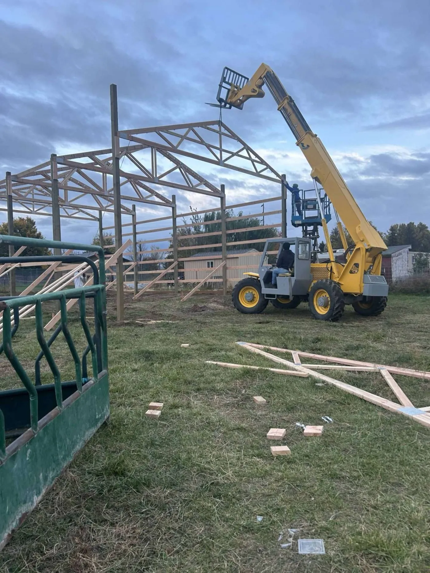 Reach forklift lifting a roof truss into place on a pole building frame